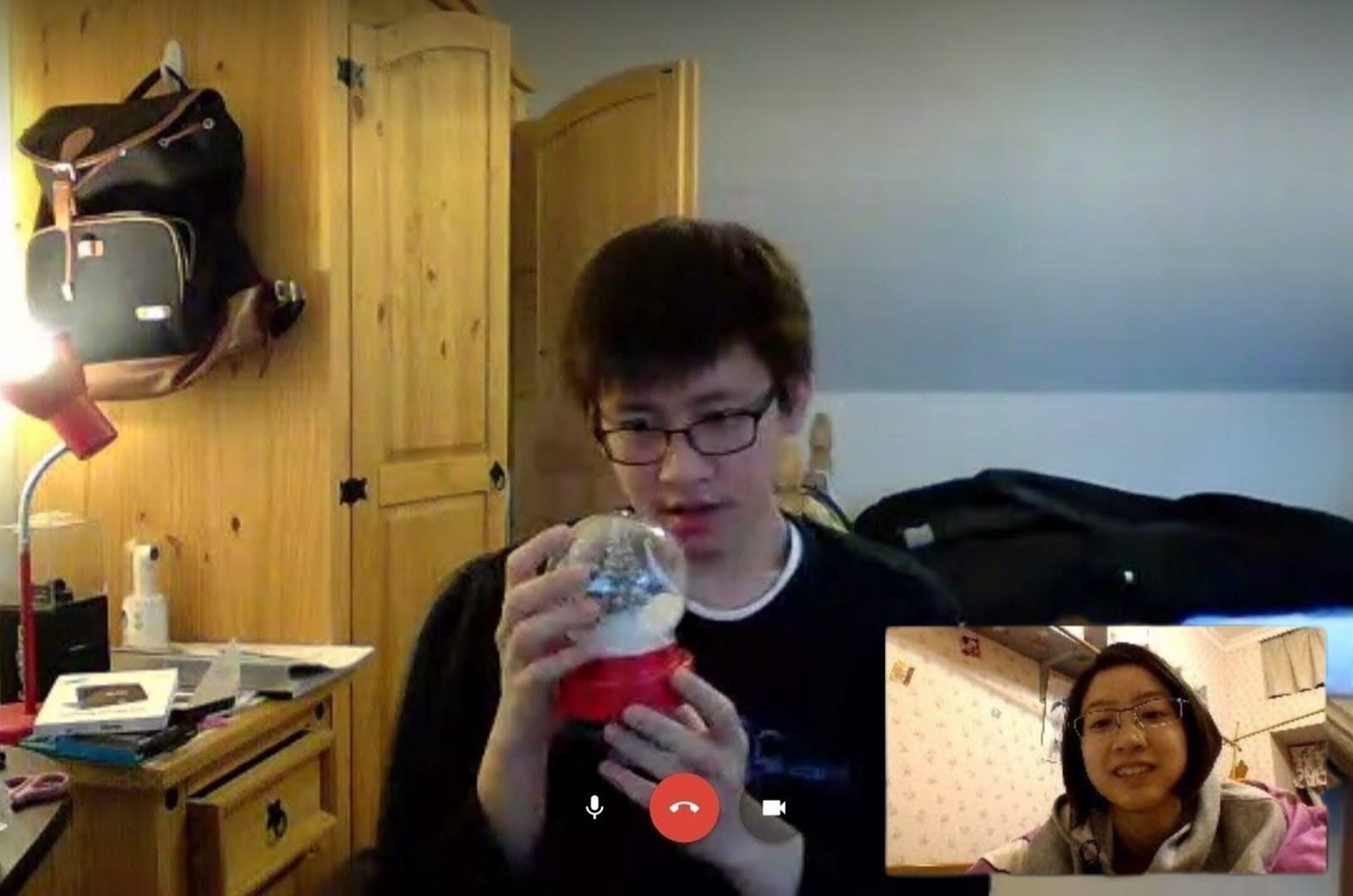 A video call from a UK dorm room — Hanny holding a snow globe up to the camera, Flora watching from the corner of the screen.
