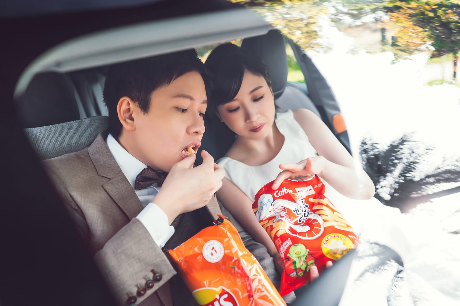 Flora and Hanny in the back seat of a car, sharing a bag of snacks.